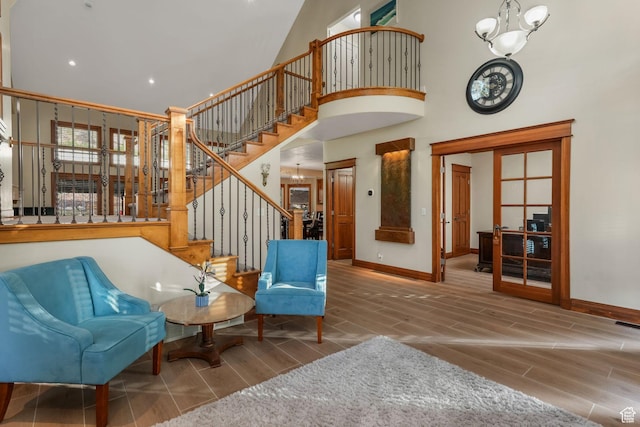 sitting room featuring wood finish floors, a high ceiling, baseboards, and stairs
