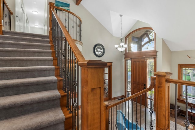 stairs with a chandelier, healthy amount of natural light, high vaulted ceiling, and baseboards