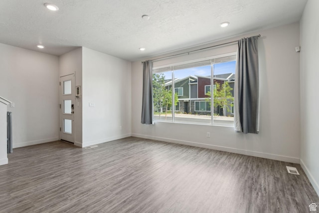 3714 W Soft Whisper Way, Herriman, UT 84096 - unfurnished living room featuring wood finished floors, baseboards, a textured ceiling, and recessed lighting