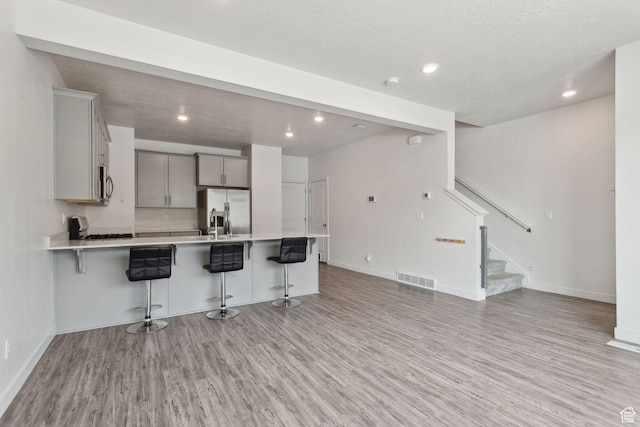 3714 W Soft Whisper Way, Herriman, UT 84096 - kitchen with stainless steel appliances, light wood-type flooring, a kitchen bar, light countertops, and baseboards