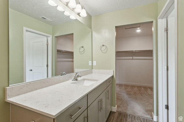 3714 W Soft Whisper Way, Herriman, UT 84096 - bathroom with vanity, baseboards, a spacious closet, wood finished floors, and a textured ceiling
