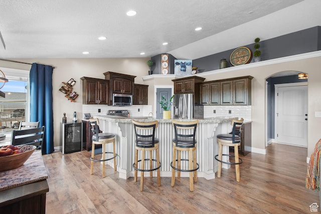 kitchen featuring appliances with stainless steel finishes, lofted ceiling, decorative backsplash, dark brown cabinetry, and a textured ceiling