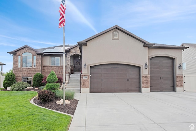 view of front facade featuring an attached garage, roof mounted solar panels, a front lawn, brick siding, and driveway