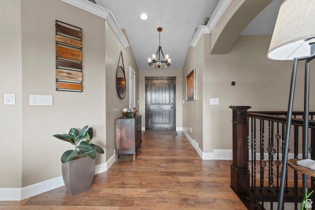 corridor featuring a chandelier, baseboards, wood finished floors, and arched walkways