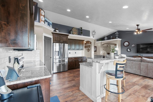 kitchen featuring stainless steel fridge with ice dispenser, range, ceiling fan, open floor plan, and lofted ceiling