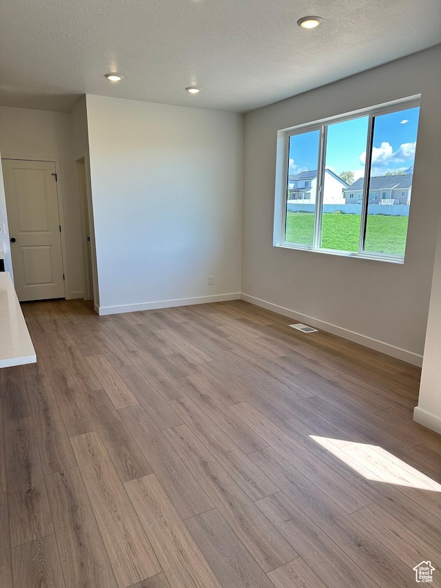 unfurnished room featuring light wood-style flooring, baseboards, recessed lighting, and a textured ceiling