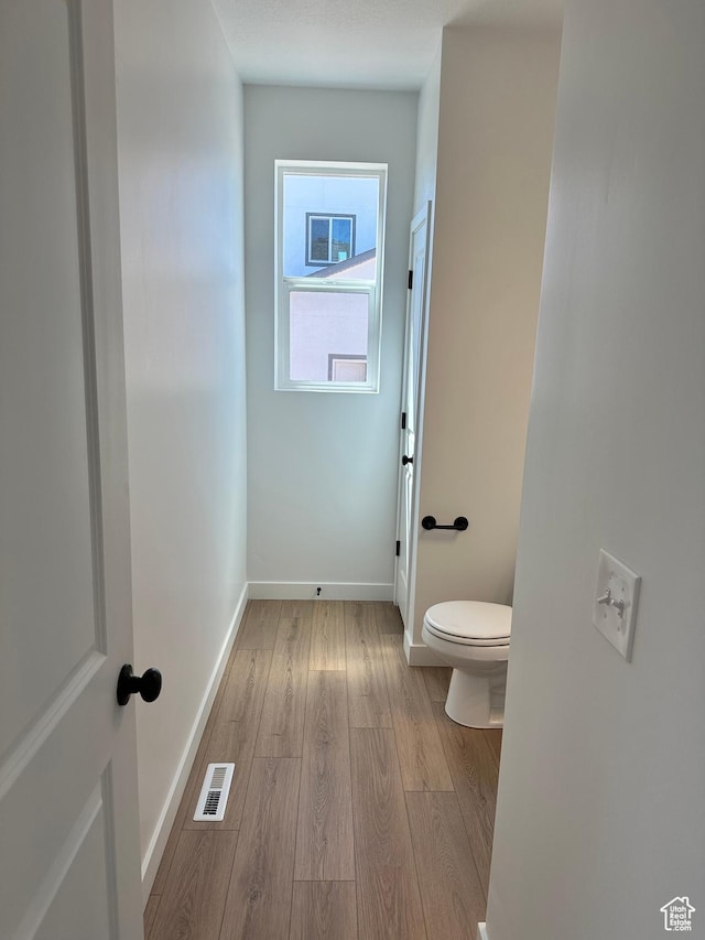 bathroom featuring wood finished floors, toilet, and baseboards