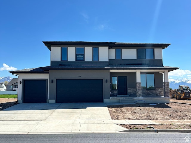 view of front of house featuring stucco siding, stone siding, driveway, an attached garage, and a porch