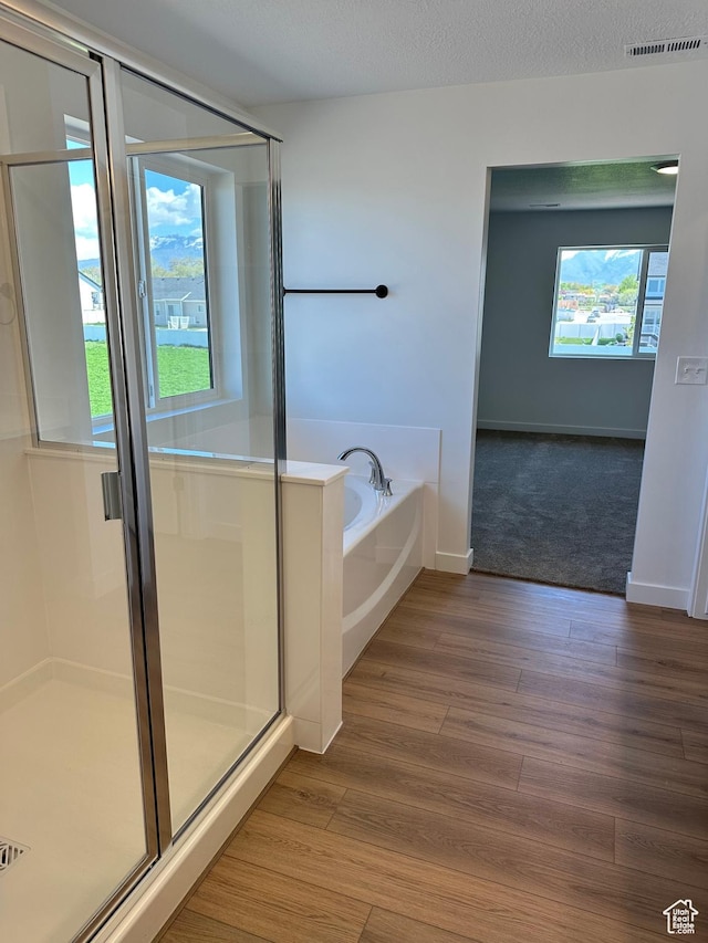 full bath with a garden tub, a stall shower, wood finished floors, and baseboards