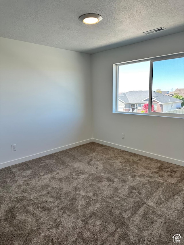 unfurnished room with carpet floors, a textured ceiling, and baseboards