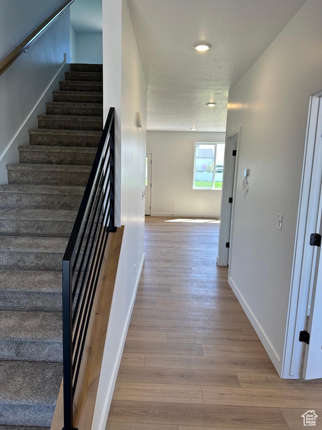 stairway featuring wood finished floors, baseboards, and recessed lighting