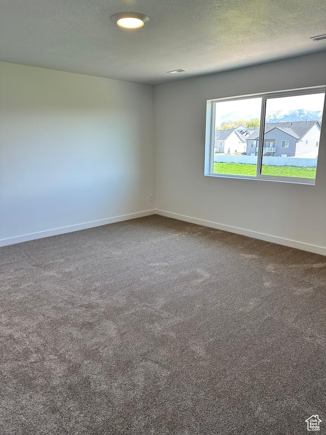 unfurnished room with baseboards, carpet floors, and a textured ceiling