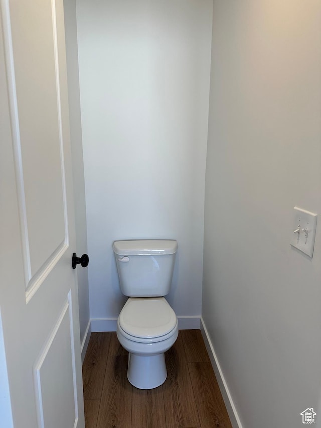 bathroom featuring wood finished floors, baseboards, and toilet