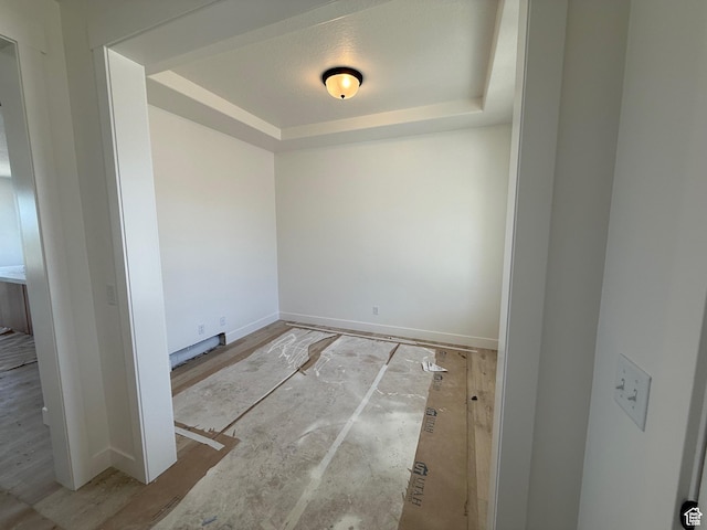 empty room featuring a raised ceiling and baseboards