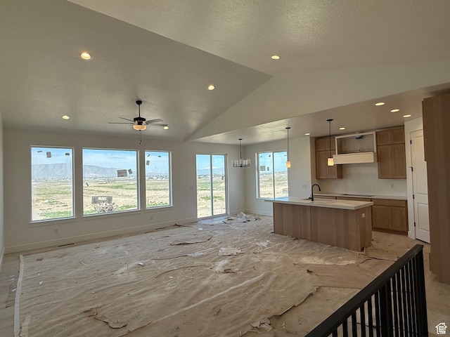 kitchen with open floor plan, baseboards, a center island with sink, recessed lighting, and lofted ceiling