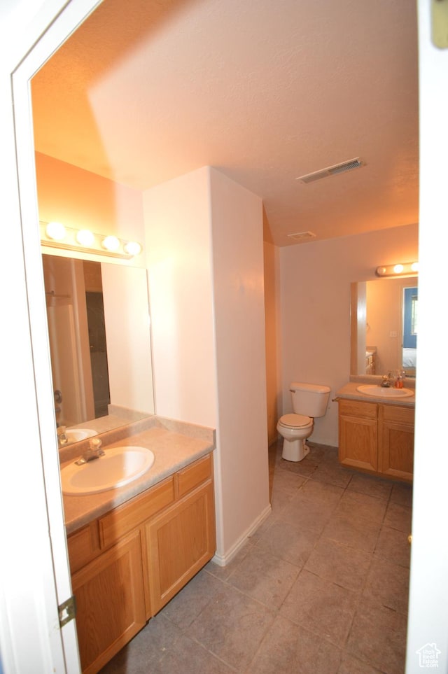 bathroom featuring toilet, vanity, baseboards, and tile patterned floors