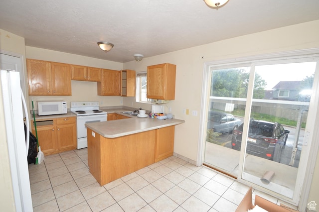 kitchen with white appliances, a peninsula, light countertops, and light tile patterned floors