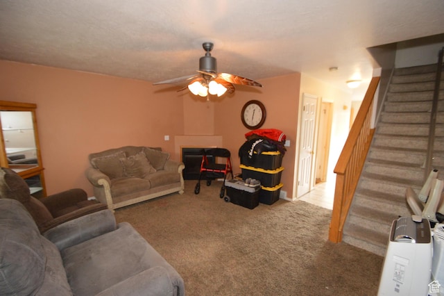 carpeted living area with stairway, ceiling fan, and a fireplace