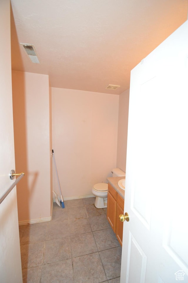 bathroom with toilet, vanity, baseboards, and tile patterned floors