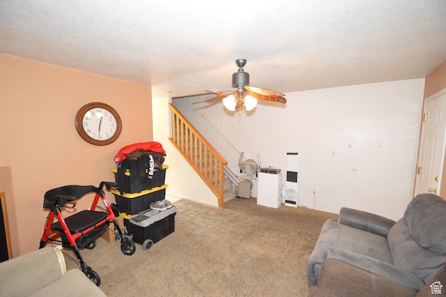 carpeted living area featuring stairs and ceiling fan