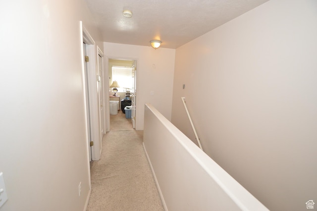 hall featuring an upstairs landing, light carpet, and baseboards