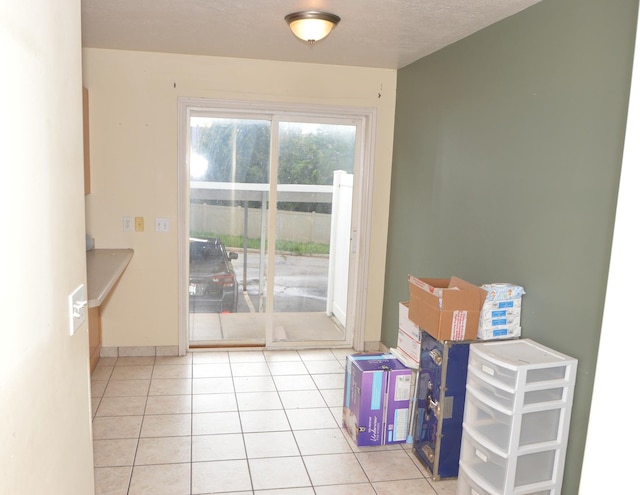 doorway to outside with tile patterned flooring and baseboards