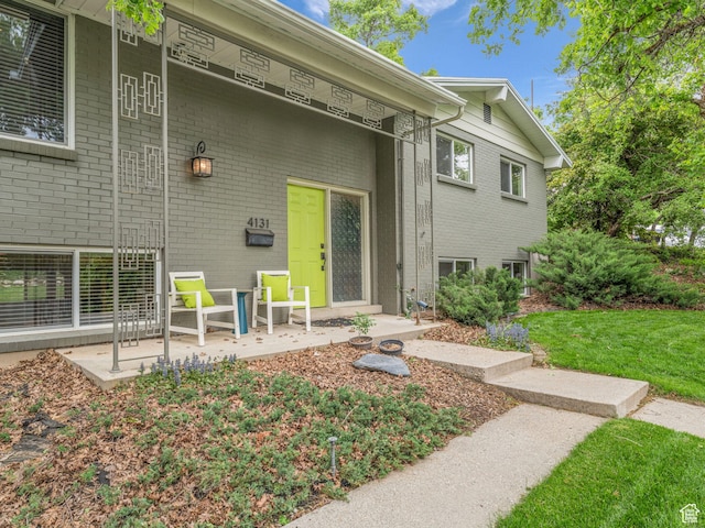4131 S Fortuna Way E, Salt Lake City, UT 84124 - doorway to property featuring brick siding and a yard