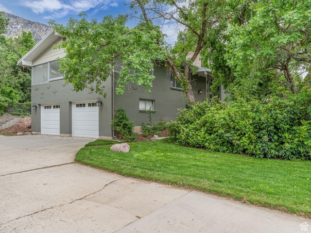 4131 S Fortuna Way E, Salt Lake City, UT 84124 - view of side of home with concrete driveway, a yard, a garage, and brick siding