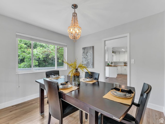 4131 S Fortuna Way E, Salt Lake City, UT 84124 - dining area featuring a chandelier, baseboards, and light wood-style floors