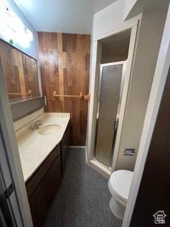 full bathroom with wood walls, a shower stall, vanity, and toilet