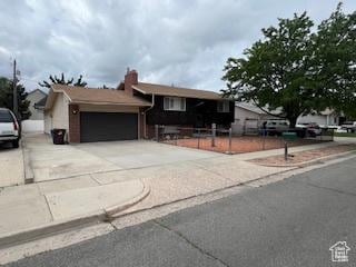 view of front of home featuring an attached garage, concrete driveway, and fence