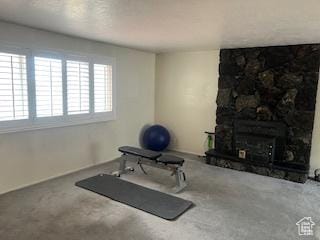 exercise room with carpet flooring and a stone fireplace