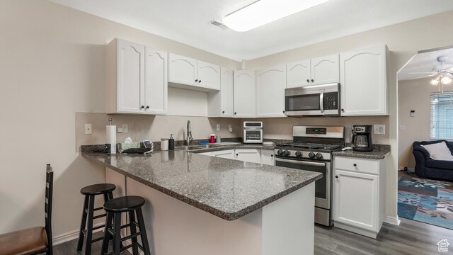 217 E 2300 N, North Ogden, UT 84414 - kitchen featuring appliances with stainless steel finishes, a sink, a peninsula, dark wood-type flooring, and white cabinetry