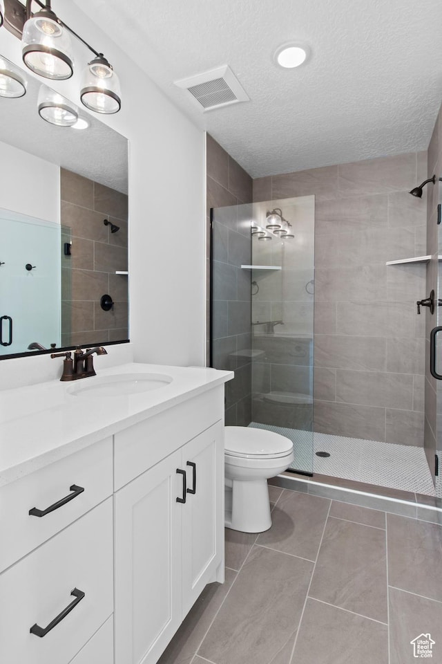 837 N 980 W Unit 66, Tremonton, UT 84337 - bathroom featuring a textured ceiling, a stall shower, toilet, vanity, and tile patterned floors