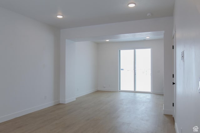 spare room featuring light wood-style floors, baseboards, a smoke detector, and recessed lighting