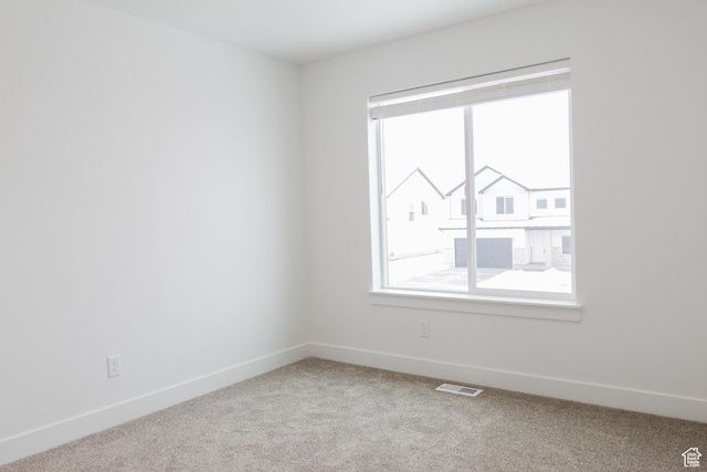unfurnished room with healthy amount of natural light, carpet flooring, and baseboards
