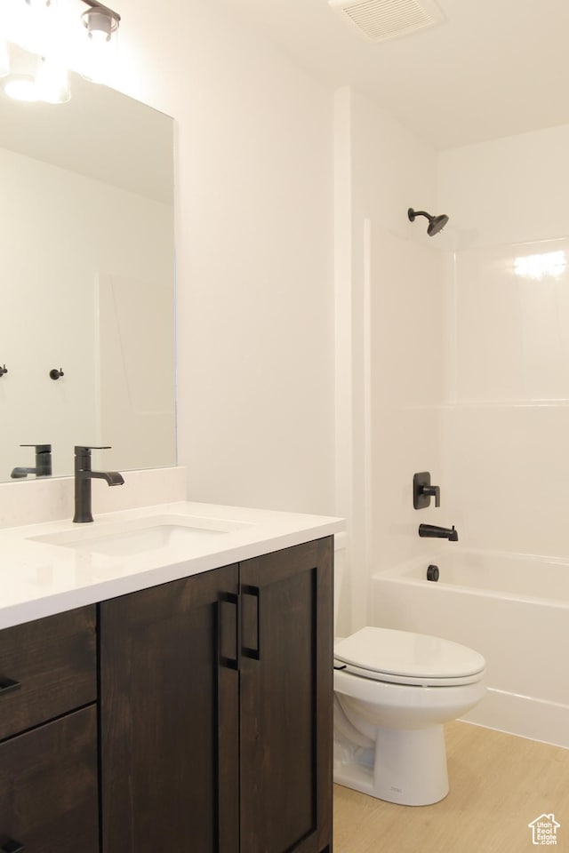 full bath featuring toilet, wood finished floors, vanity, and tub / shower combination