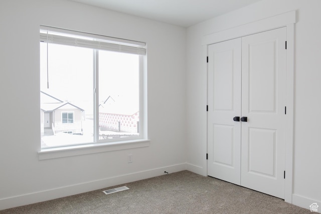 unfurnished bedroom with carpet floors, a closet, and baseboards