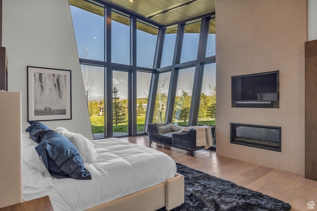 800 Hollyhock St, Park City, UT 84098 - bedroom with a towering ceiling, a glass covered fireplace, wood finished floors, multiple windows, and a wall of windows