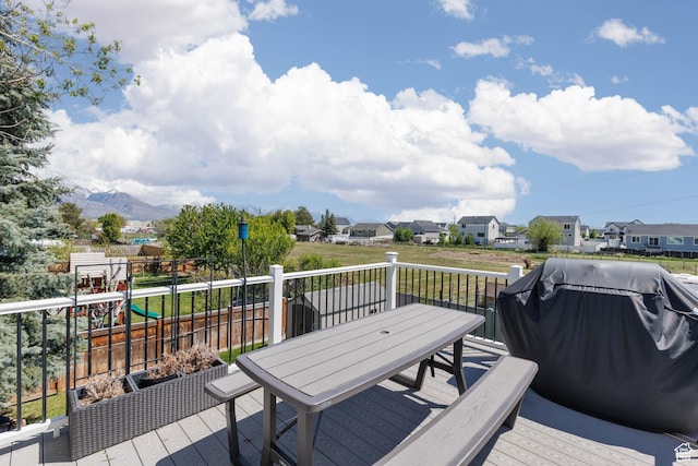 wooden deck featuring outdoor dining space, a residential view, and a mountain view