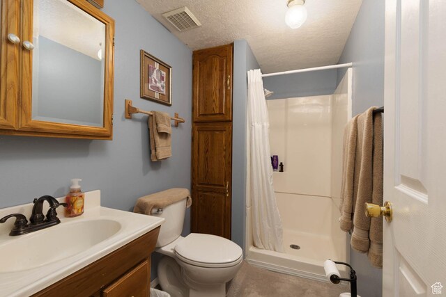 full bath featuring a shower stall, toilet, vanity, and a textured ceiling