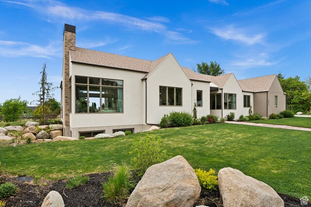 10076 S Wild Goose Cv E, Sandy, UT 84092 - view of front facade featuring a chimney, stucco siding, a front yard, and roof with shingles