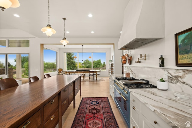 10076 S Wild Goose Cv E, Sandy, UT 84092 - kitchen featuring high end range, premium range hood, recessed lighting, backsplash, and white cabinetry