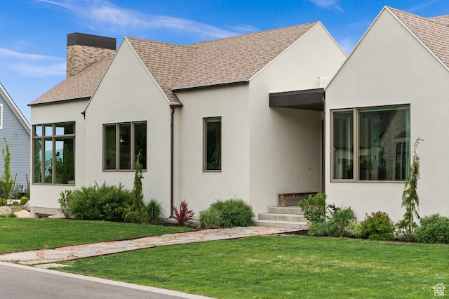 10076 S Wild Goose Cv E, Sandy, UT 84092 - view of front of home featuring stucco siding, a chimney, roof with shingles, and a front lawn