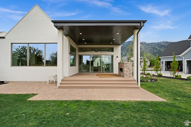 10076 S Wild Goose Cv E, Sandy, UT 84092 - rear view of property with stucco siding, a lawn, a mountain view, and a patio