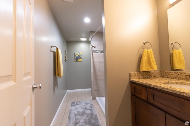 full bathroom featuring tiled shower, vanity, tile patterned floors, baseboards, and recessed lighting