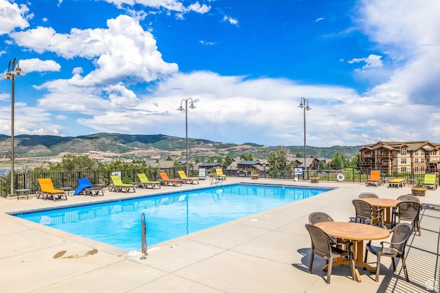 community pool featuring fence, a mountain view, and a patio