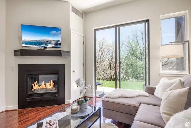 living room featuring a glass covered fireplace, wood finished floors, and baseboards