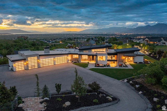 contemporary house featuring a mountain view, a garage, concrete driveway, and a yard