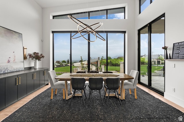 dining room featuring light wood-type flooring and a towering ceiling